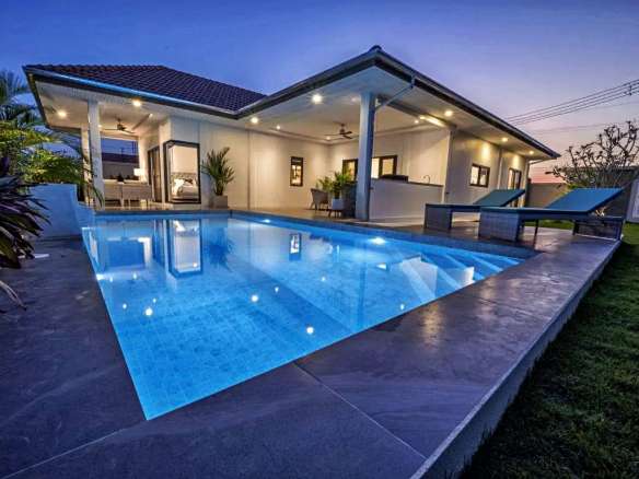 Luxury modern villa with illuminated private swimming pool at dusk