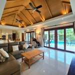 Luxury open-plan living room with high wooden ceiling, ceiling fans, and pool access