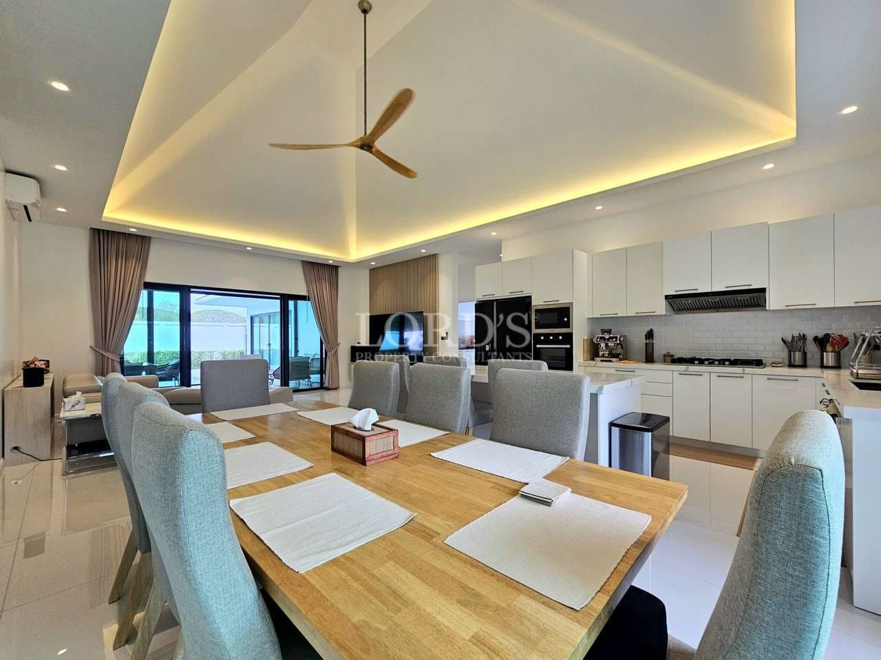 Open-plan dining and kitchen area with wooden dining table, modern cabinetry, and ambient ceiling lighting