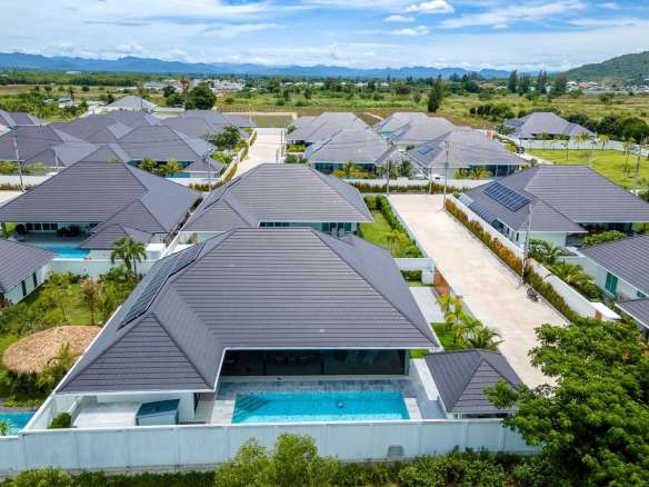 Aerial view of luxury villa community with private swimming pools, landscaped gardens, and mountain views