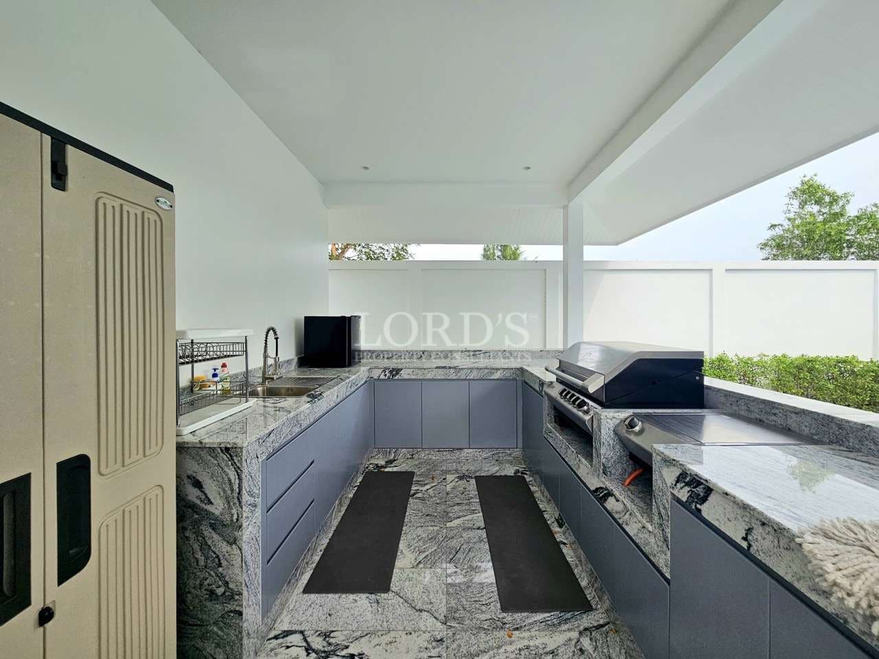 Outdoor kitchen with built-in grill, stone countertops, and modern cabinetry