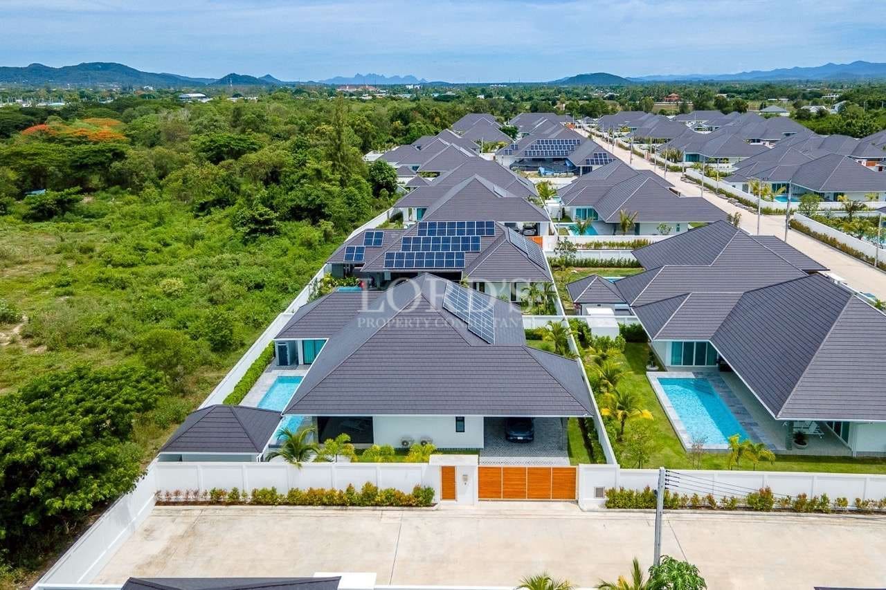 Aerial view of modern residential villas with private pools, solar panels, and landscaped surroundings