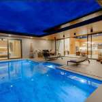 Luxury modern villa at night with illuminated private swimming pool and outdoor seating area.