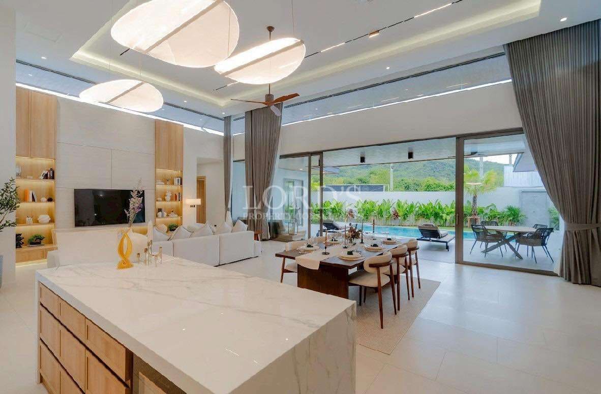 Luxury open-plan living and dining area with modern kitchen island and pool view.