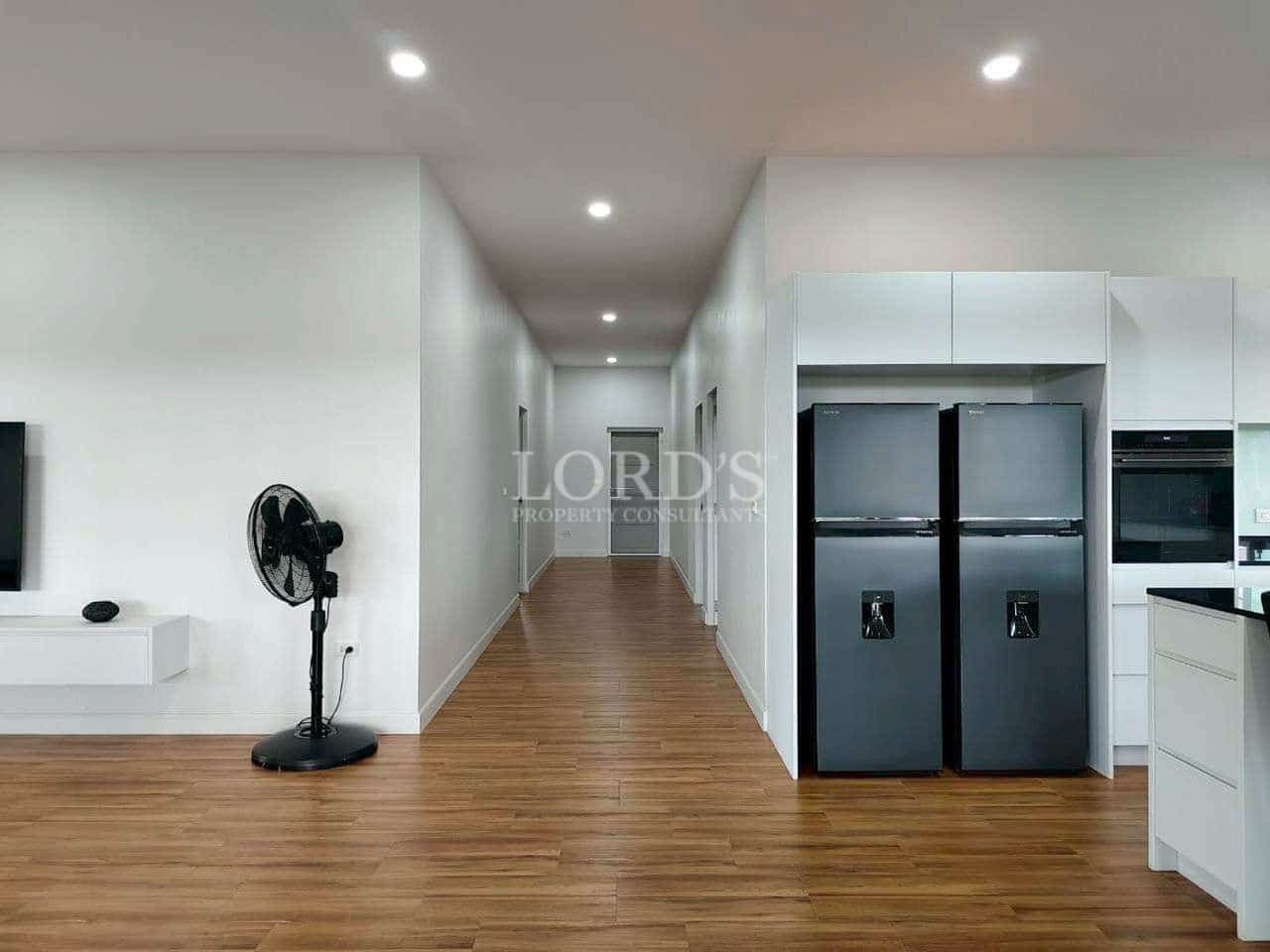 Modern interior hallway with wooden flooring, recessed ceiling lights, and built-in kitchen appliances.
