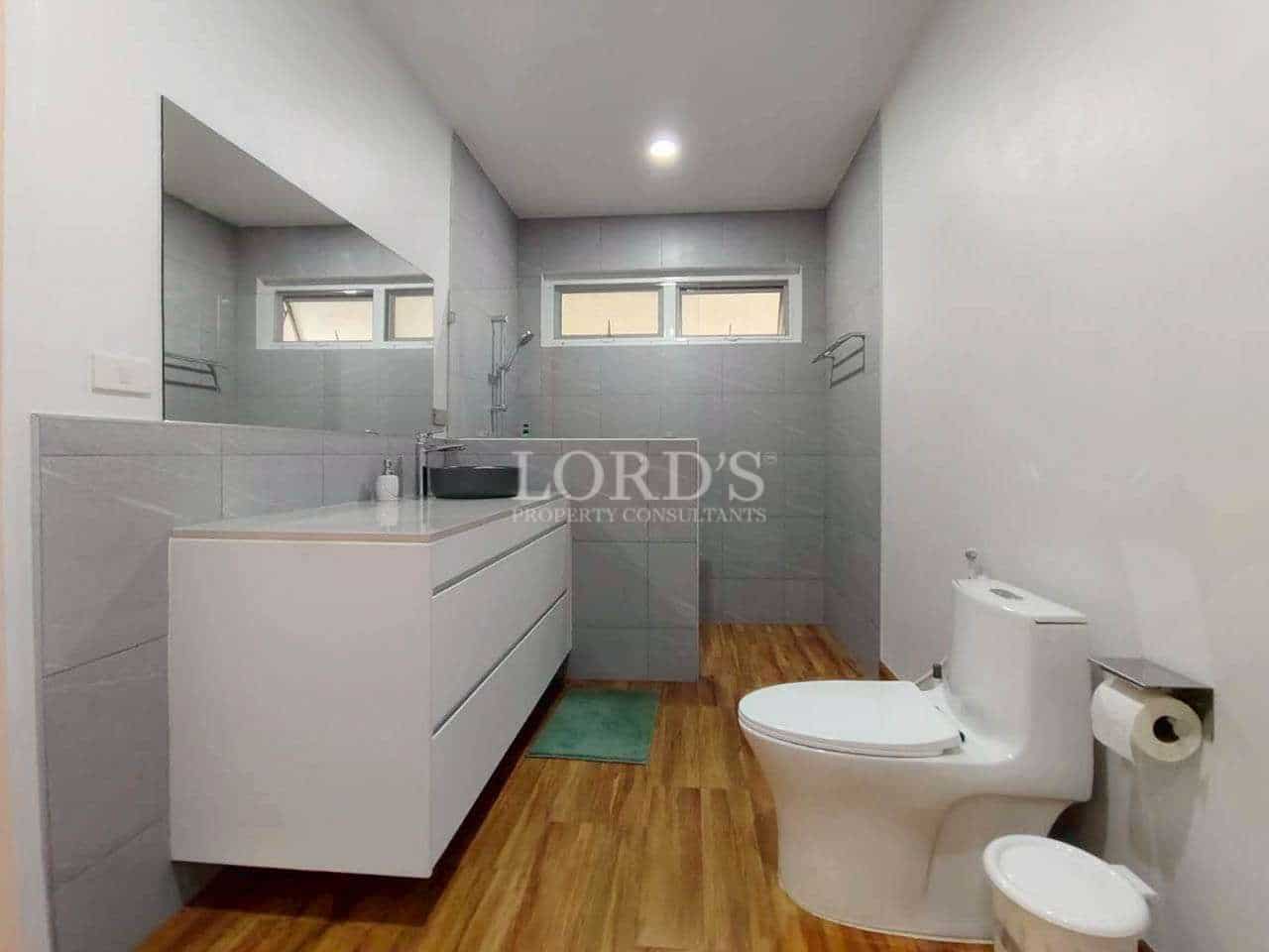 Modern bathroom with walk-in shower, vanity unit, toilet, and wooden-style flooring.