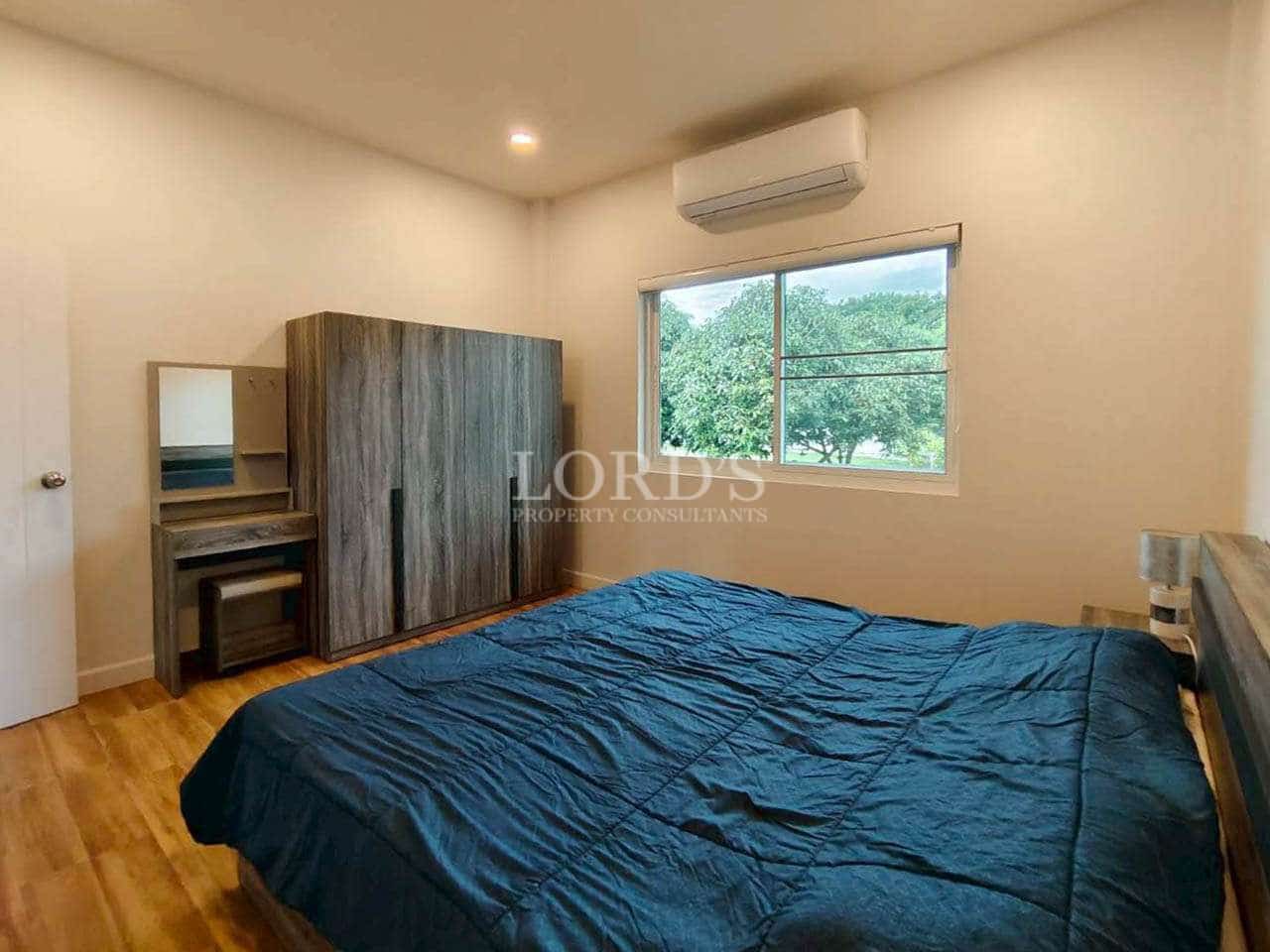 Bedroom with wooden flooring, double bed, wardrobe, air conditioning, and garden view.