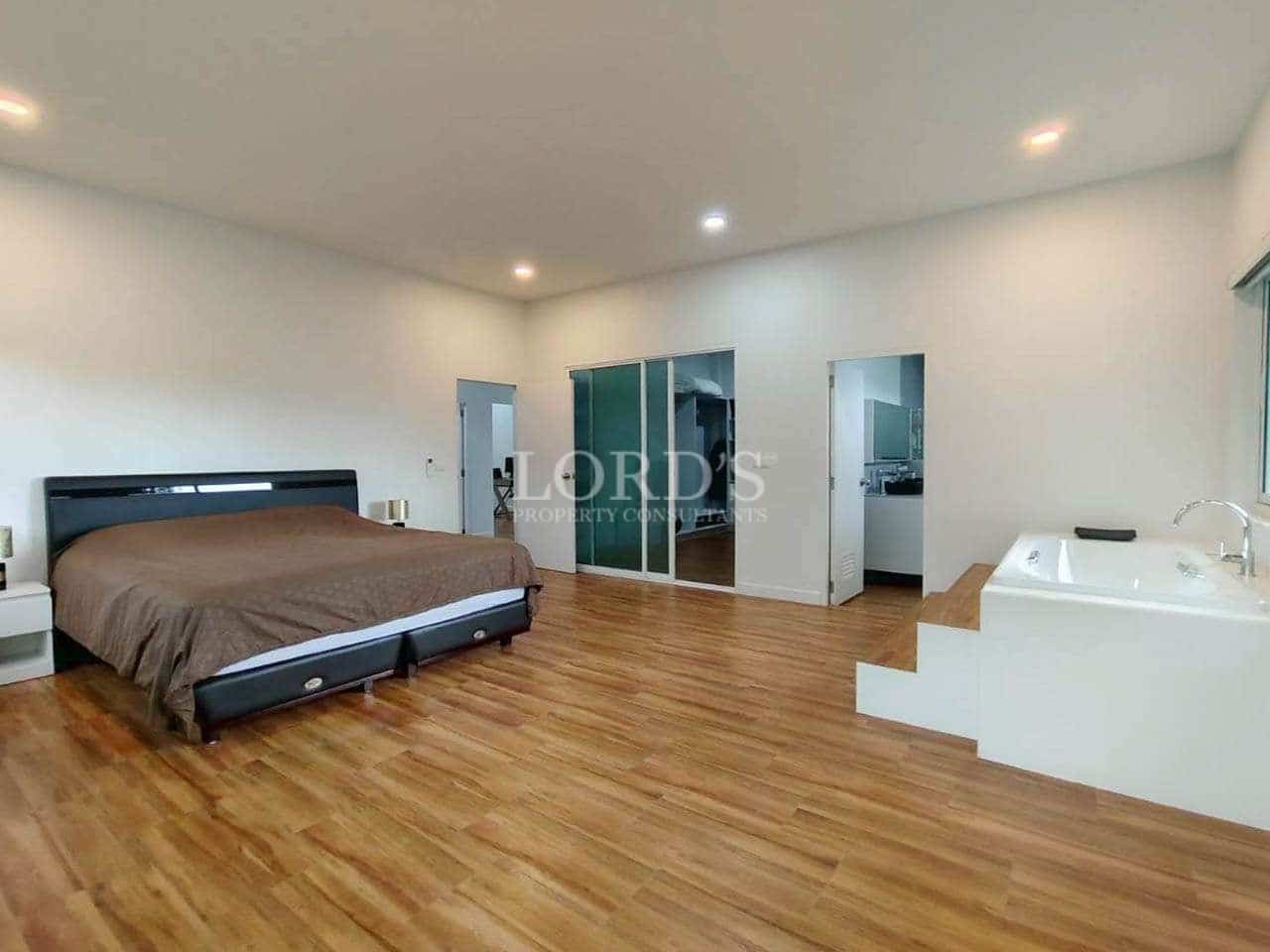 Spacious master bedroom with indoor bathtub, wooden floors, and modern open layout.