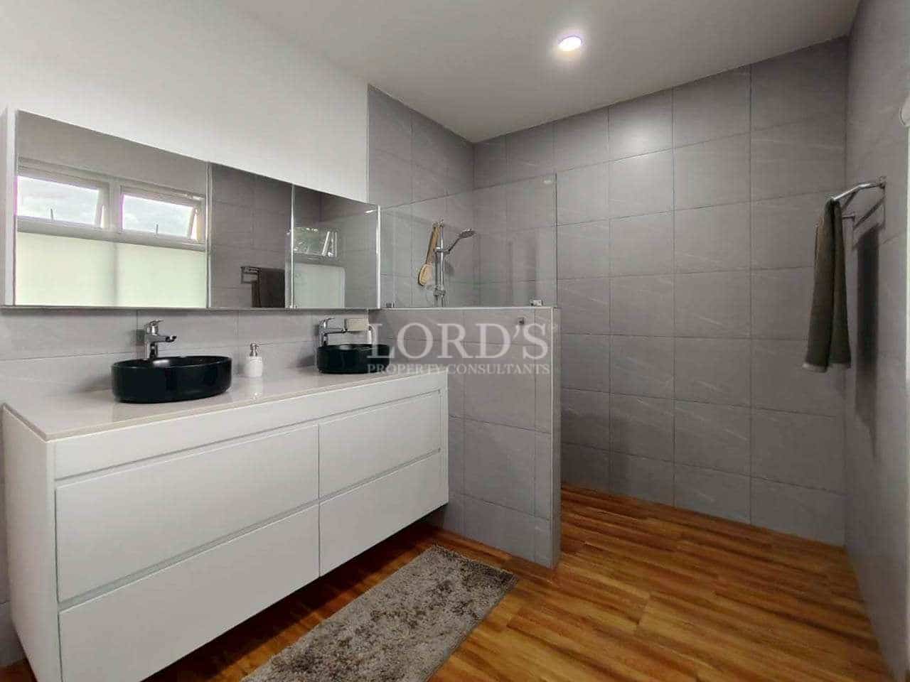 Modern bathroom with double vanity, black vessel sinks, walk-in shower, gray tiles, and wooden flooring.