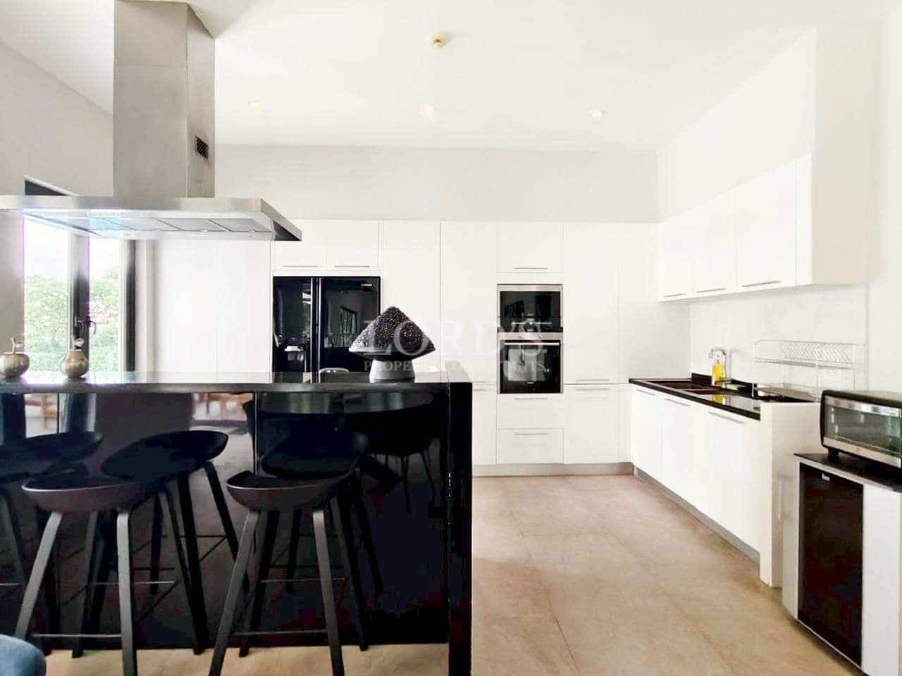 Modern white kitchen with black island, built-in appliances, and minimalist design