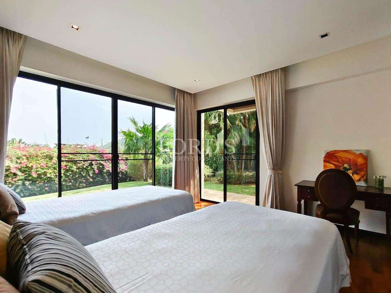 Luxury twin bedroom with garden view, floor-to-ceiling glass doors, and natural light.