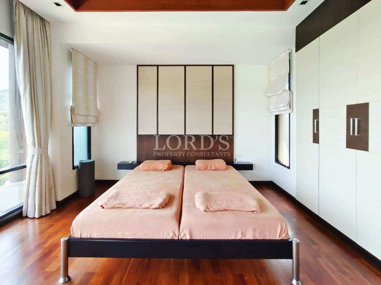 Modern twin bedroom with wooden flooring, minimalist design, built-in wardrobe, and soft natural lighting.
