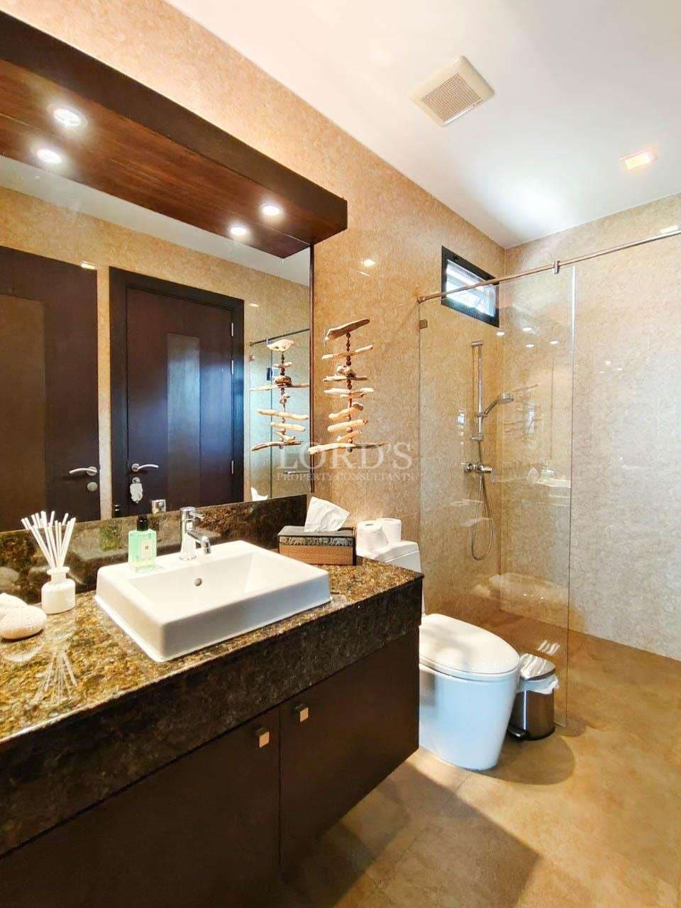 Modern bathroom with glass shower enclosure, stone tiles, vanity sink, and luxury fixtures.