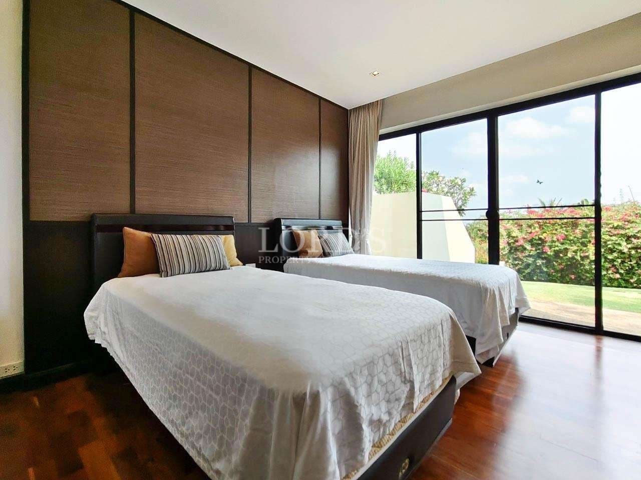 Twin bedroom with wooden flooring, modern panel wall, and large sliding glass doors opening to a garden view.