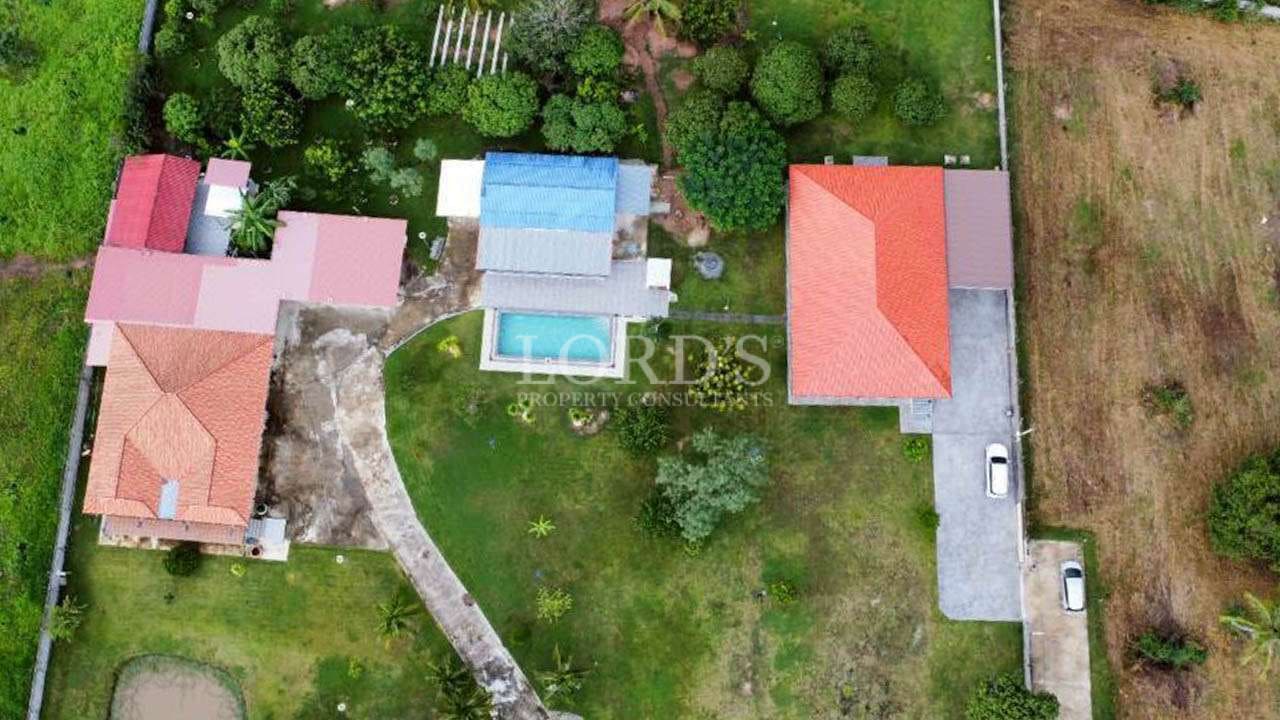Aerial view of private villa compound with swimming pool, garden, and multiple buildings.