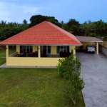 Front exterior view of a single-story villa with red-tiled roof, private driveway, and covered parking.
