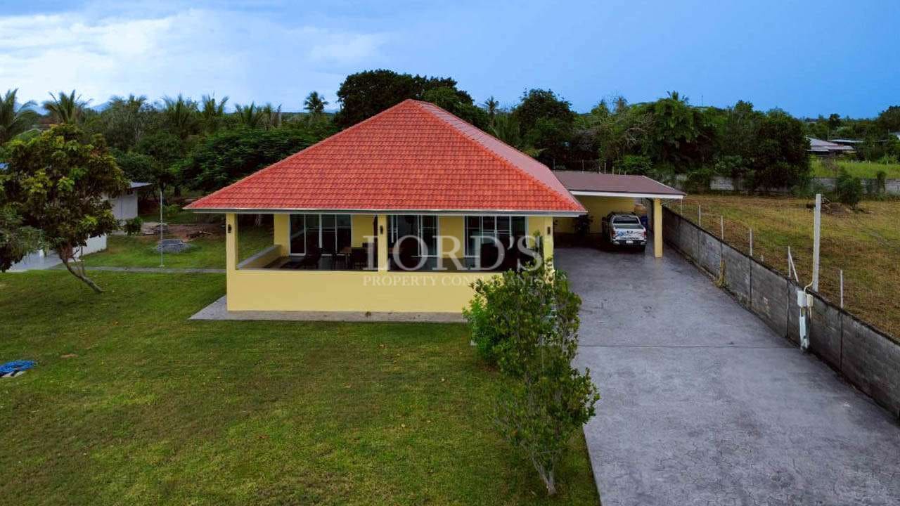 Front exterior view of a single-story villa with red-tiled roof, private driveway, and covered parking.