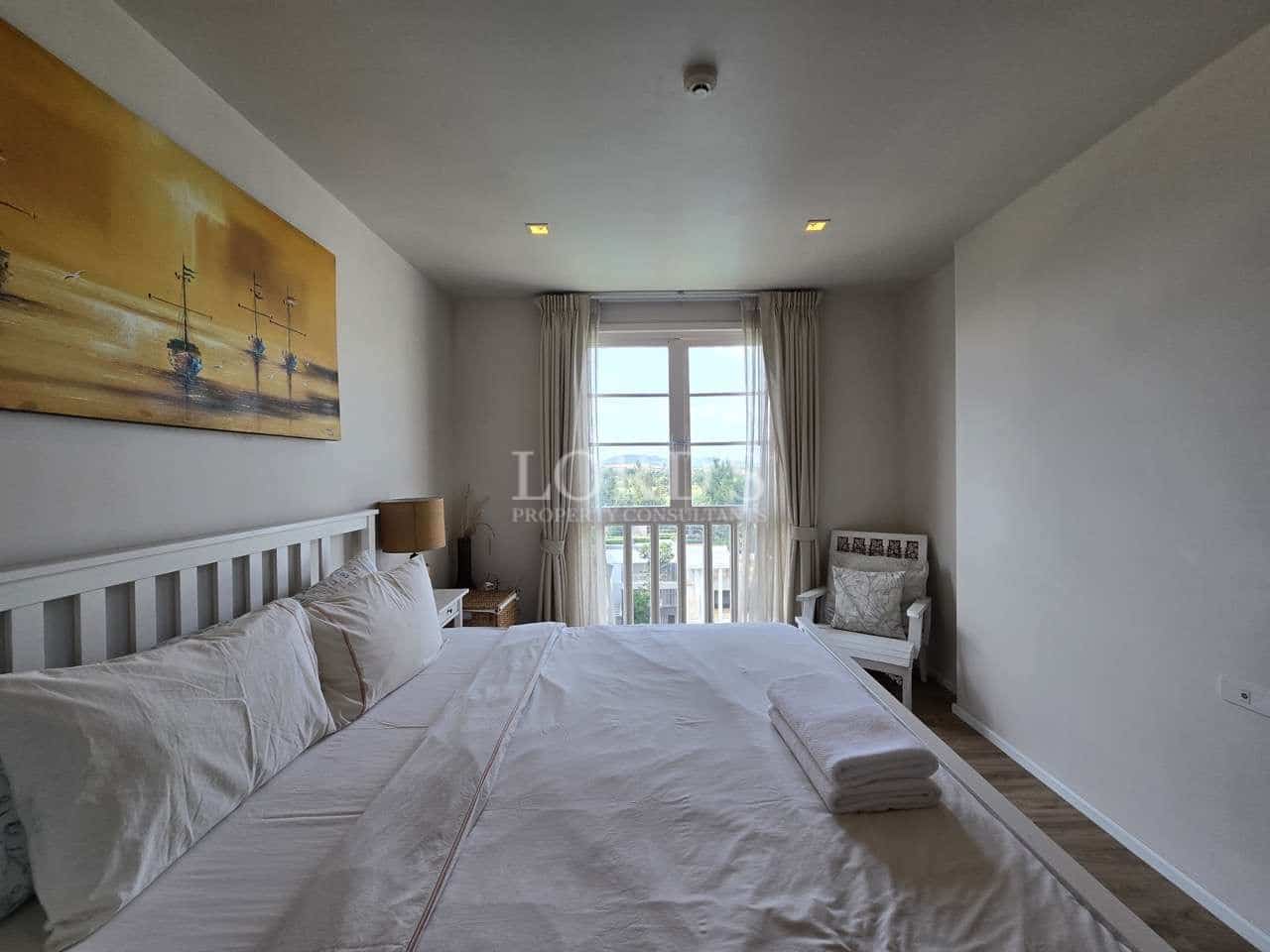 Bright bedroom with double bed, artwork, and window with natural light