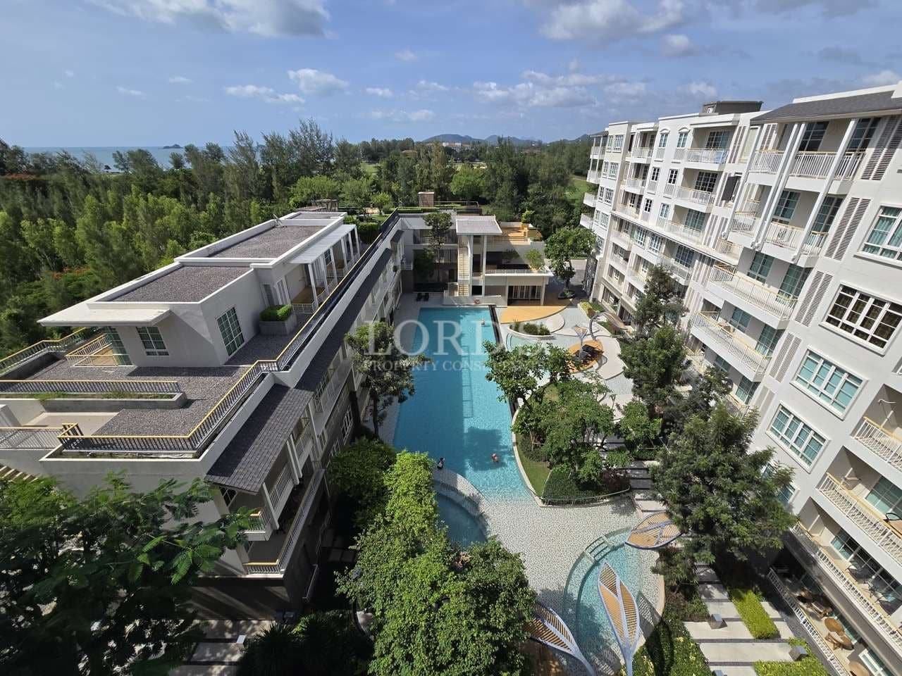 Aerial view of modern residential complex with central swimming pool and landscaped gardens
