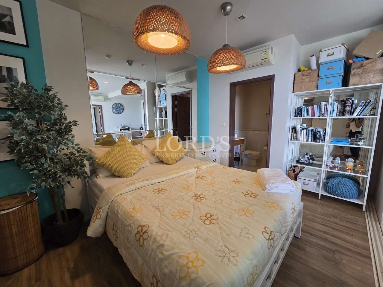 Cozy modern bedroom with double bed, pendant lights, mirror wall, and storage shelves