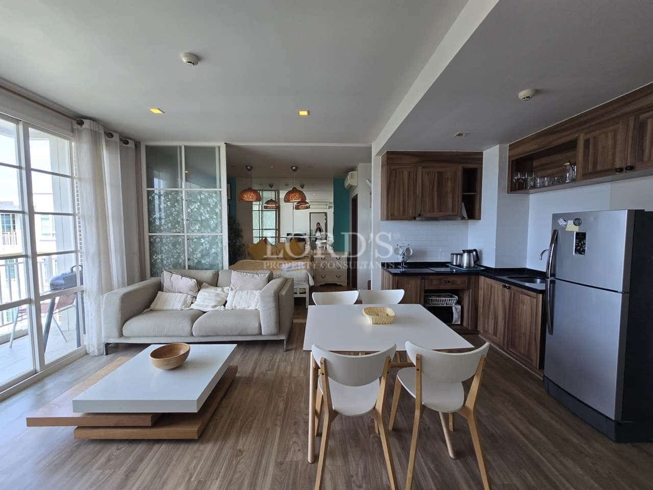 Modern open-plan apartment with living room, dining area, kitchen, and balcony access