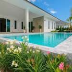 Modern luxury villa with a private swimming pool, landscaped garden, and covered outdoor terrace under a clear blue sky.