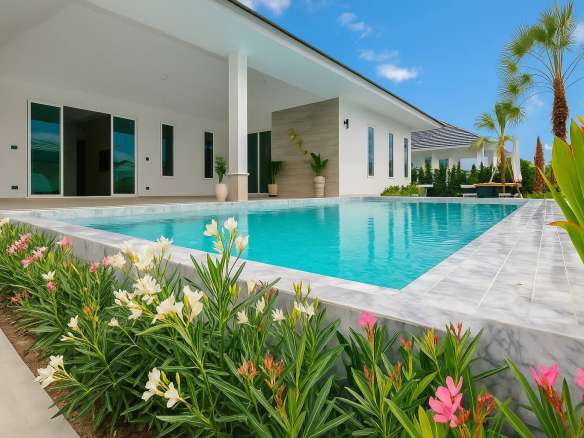 Modern luxury villa with a private swimming pool, landscaped garden, and covered outdoor terrace under a clear blue sky.