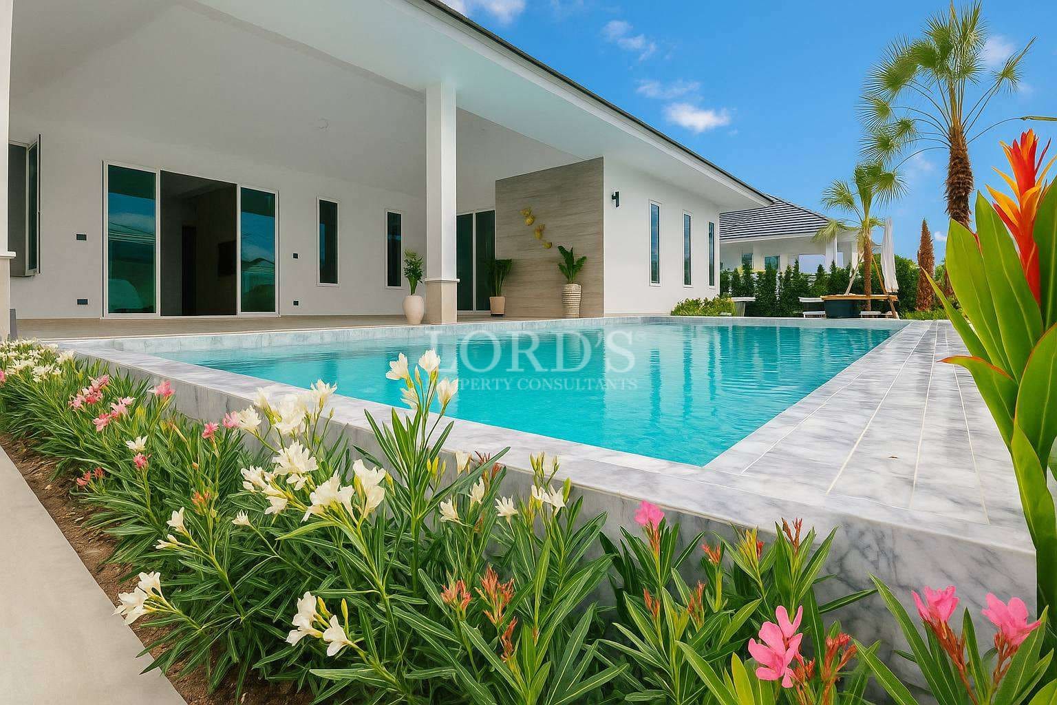 Modern luxury villa with a private swimming pool, landscaped garden, and covered outdoor terrace under a clear blue sky.