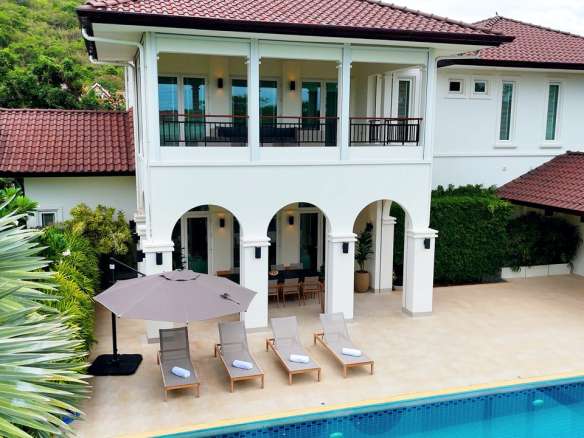 Luxury two-story villa with private swimming pool, balcony, and poolside sun loungers.