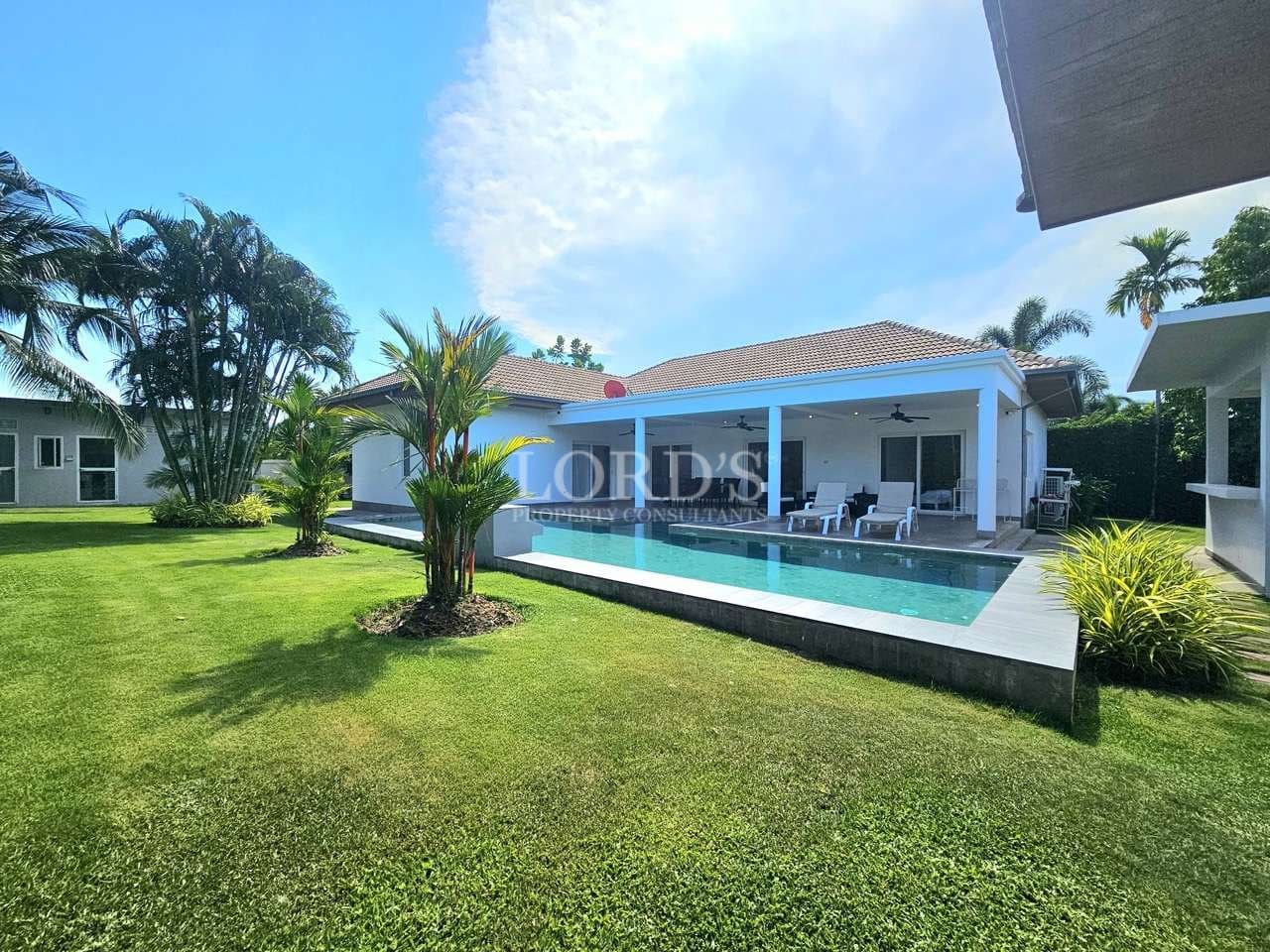 Modern luxury villa with private swimming pool, covered patio, sun loungers, and landscaped tropical garden.
