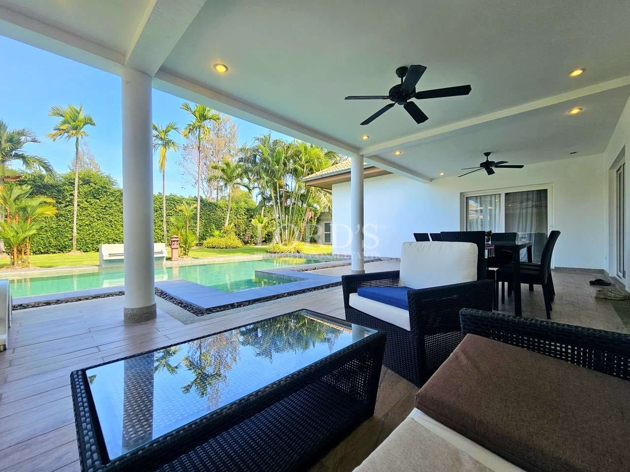 Covered poolside terrace with outdoor seating, ceiling fans, and private swimming pool in a tropical luxury villa.