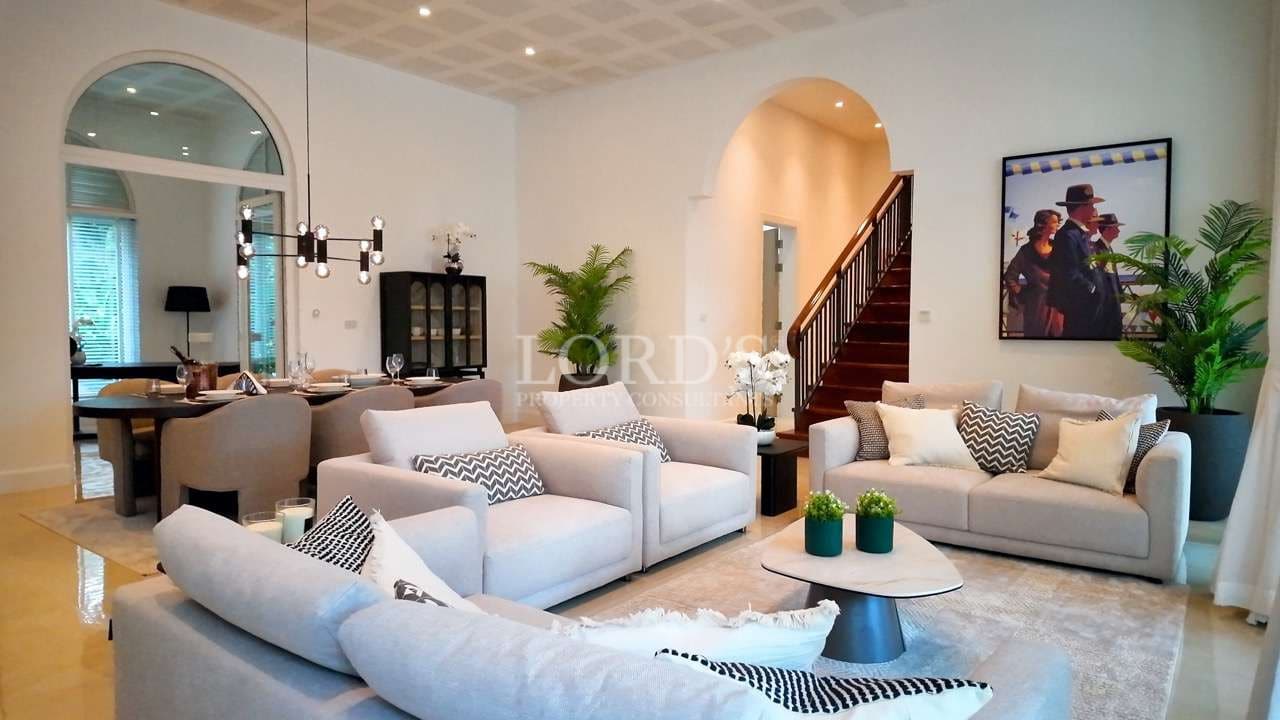 Luxury open-plan living and dining room with modern sofas, staircase, and elegant lighting.