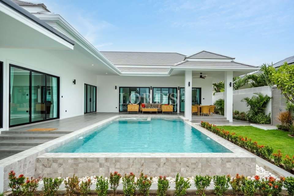 Modern luxury villa with a private swimming pool, white exterior, large glass doors, and landscaped garden.