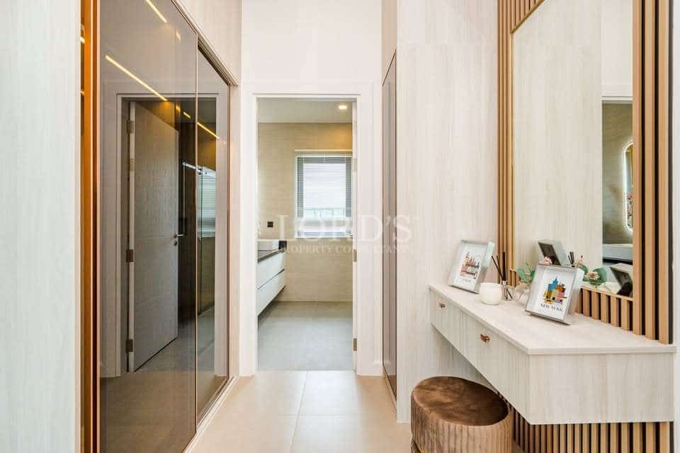 Modern villa dressing hallway with built-in vanity, full-height mirror, and walk-in closet leading to ensuite bathroom