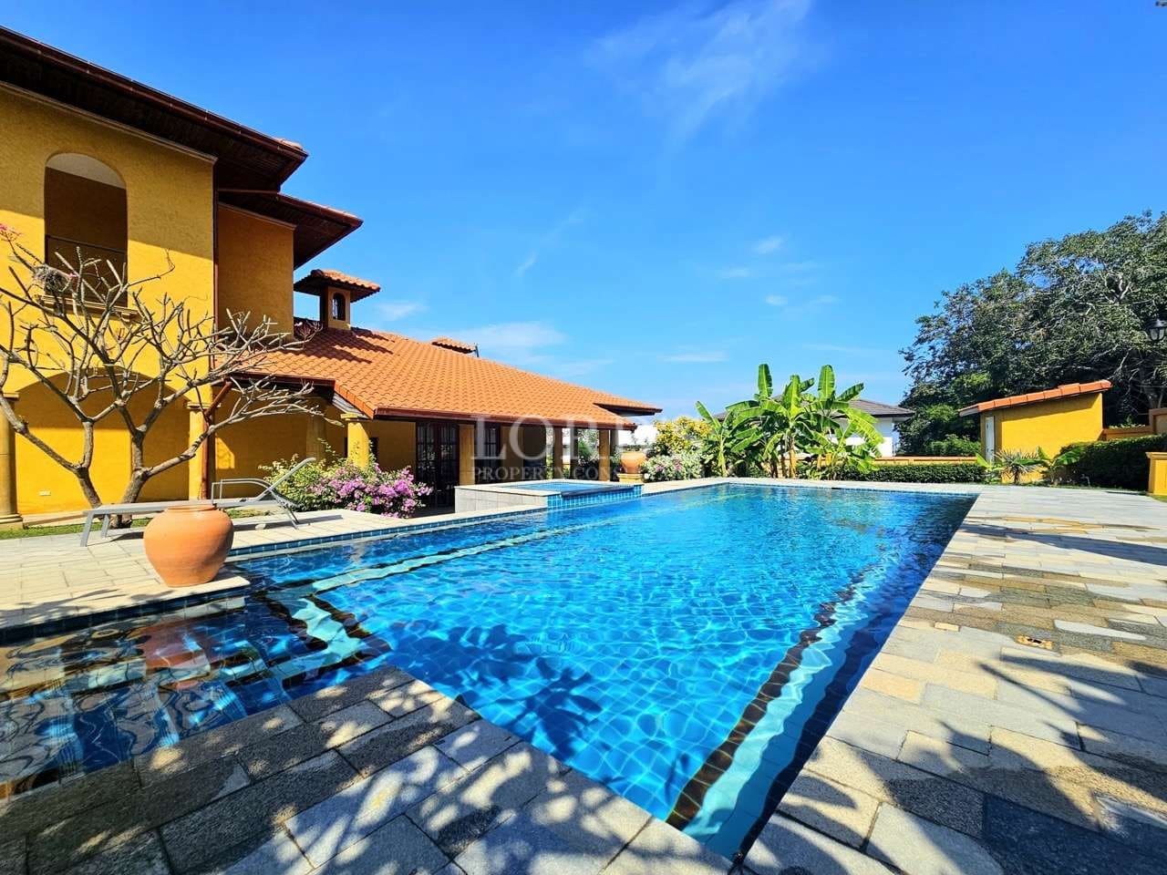 Luxury villa swimming pool with blue tiles, landscaped garden, and Mediterranean-style architecture.