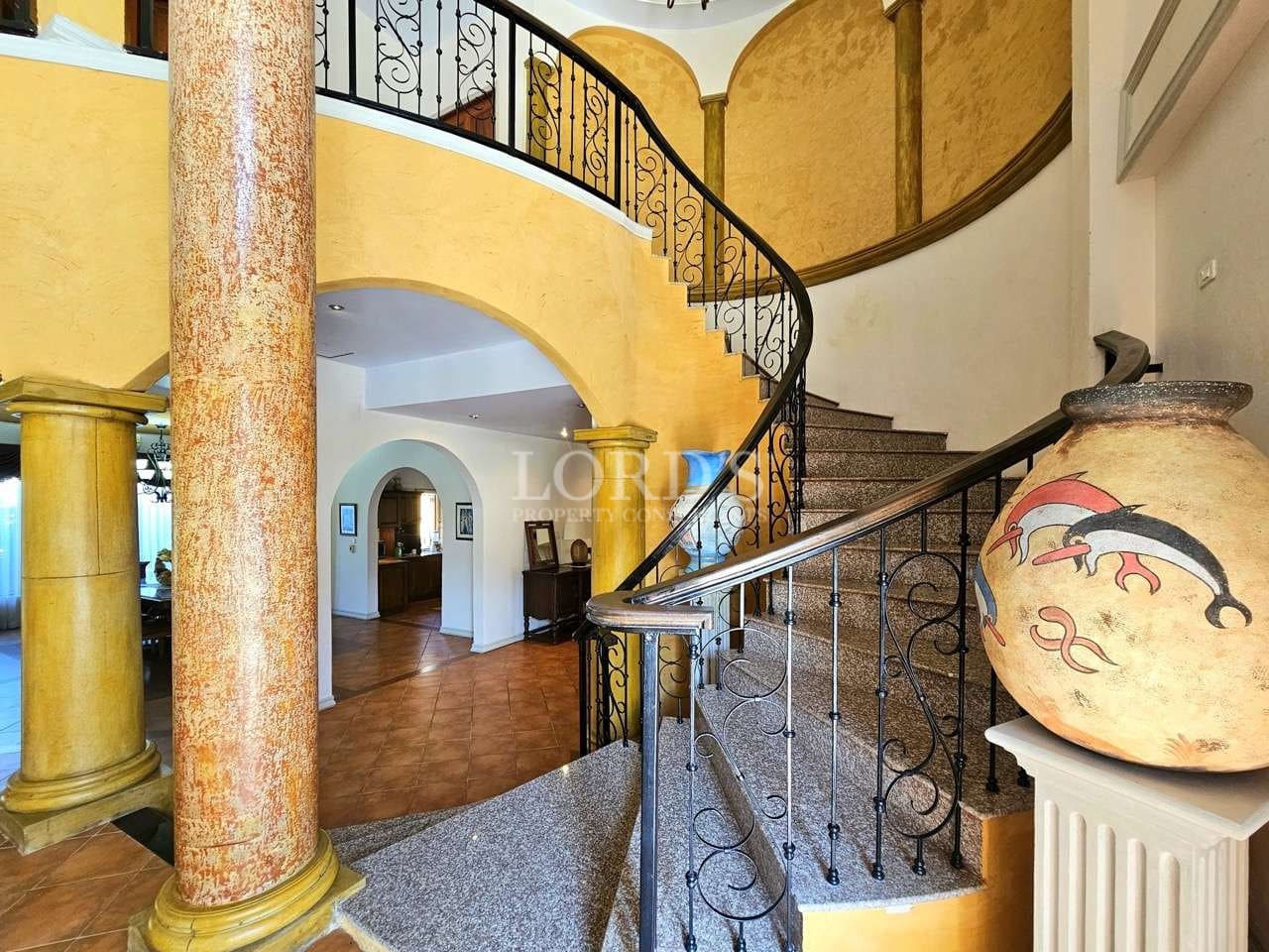 Luxury villa interior featuring a curved staircase, arched columns, and Mediterranean-style design.