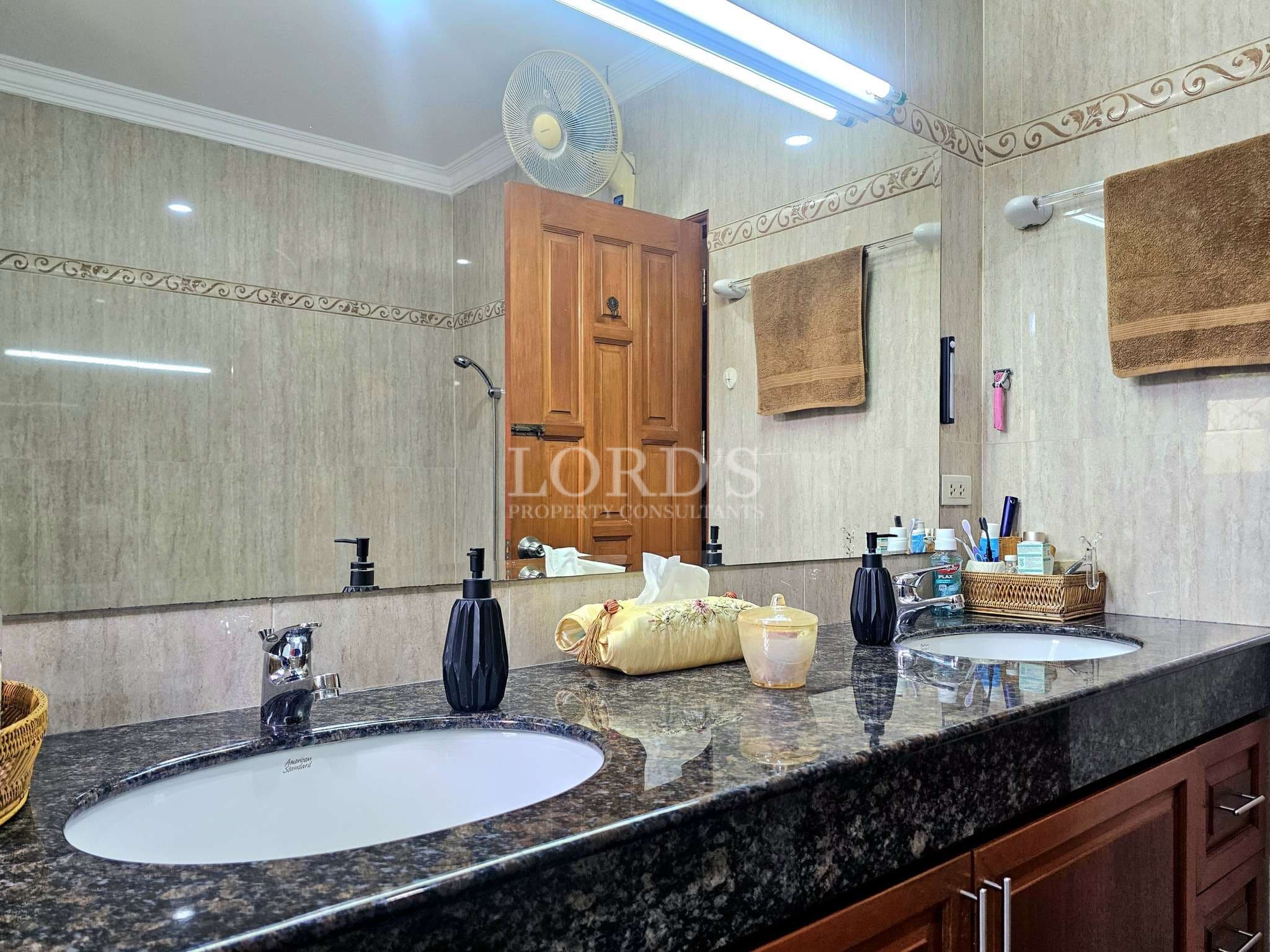 Modern bathroom with double sink vanity, granite countertop, large mirror, and wooden cabinets