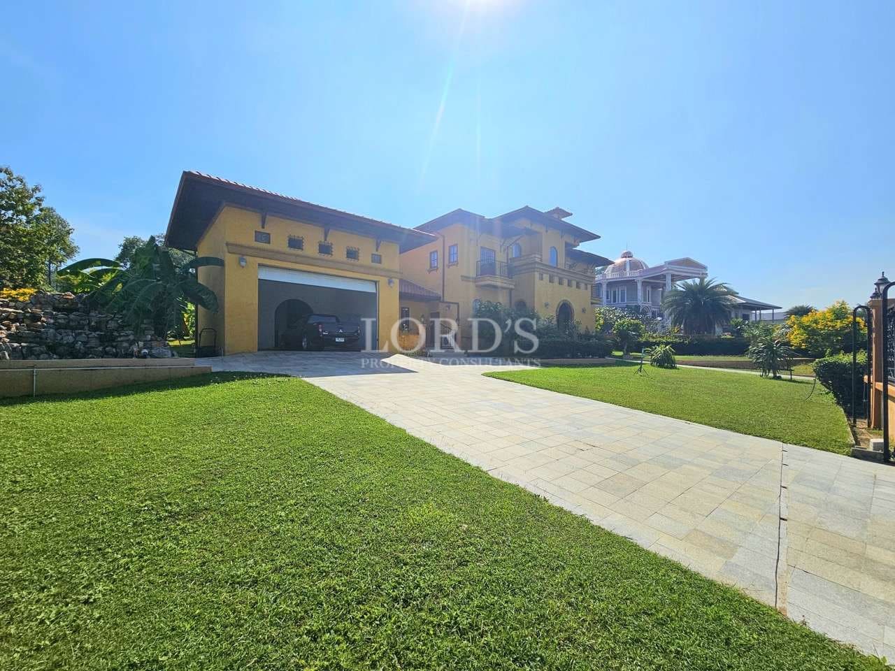 Luxury villa exterior with private driveway, landscaped lawn, and covered garage.