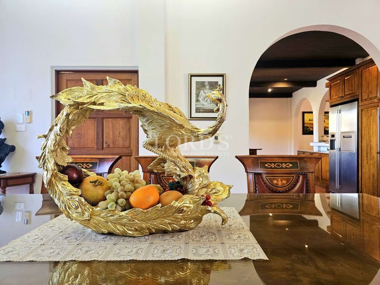 Elegant dining table centerpiece featuring a gold sculptural fruit bowl in a luxury villa interior.