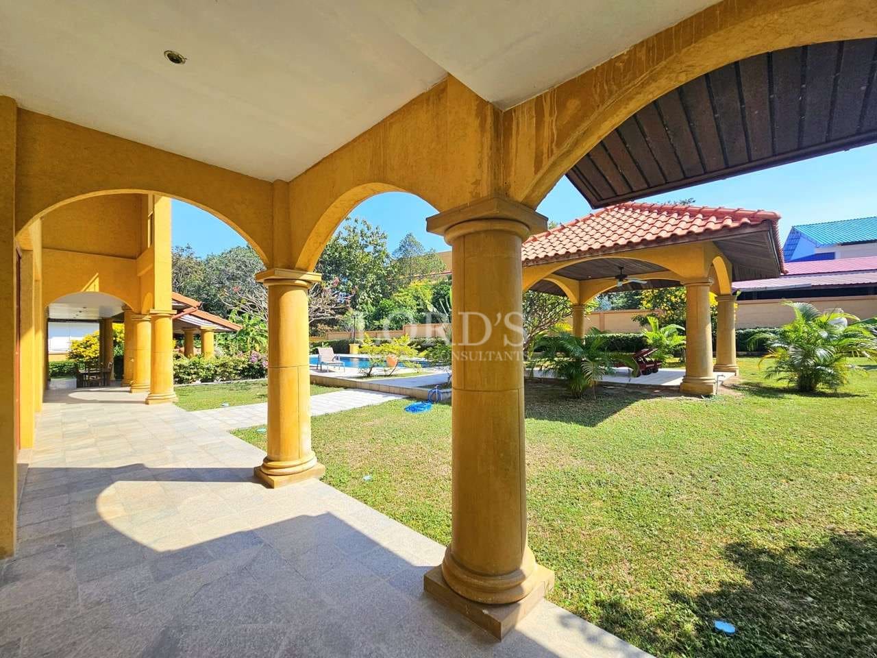 Luxury villa courtyard with arched columns, covered outdoor walkway, landscaped garden, and Mediterranean-style architecture.