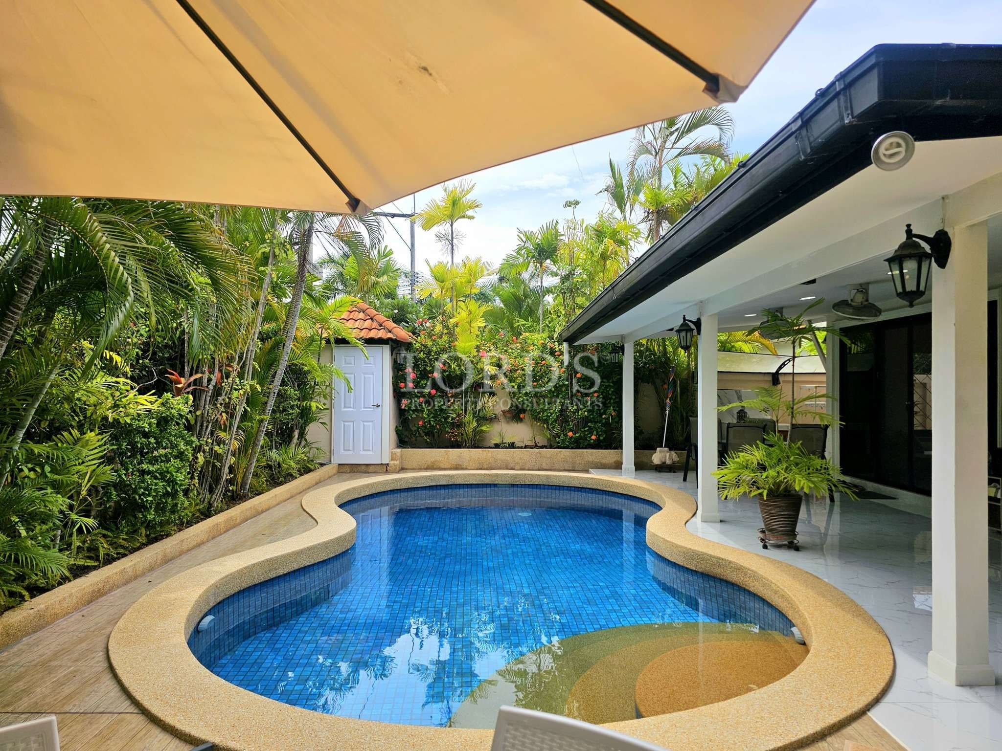 Tropical poolside with lush greenery.