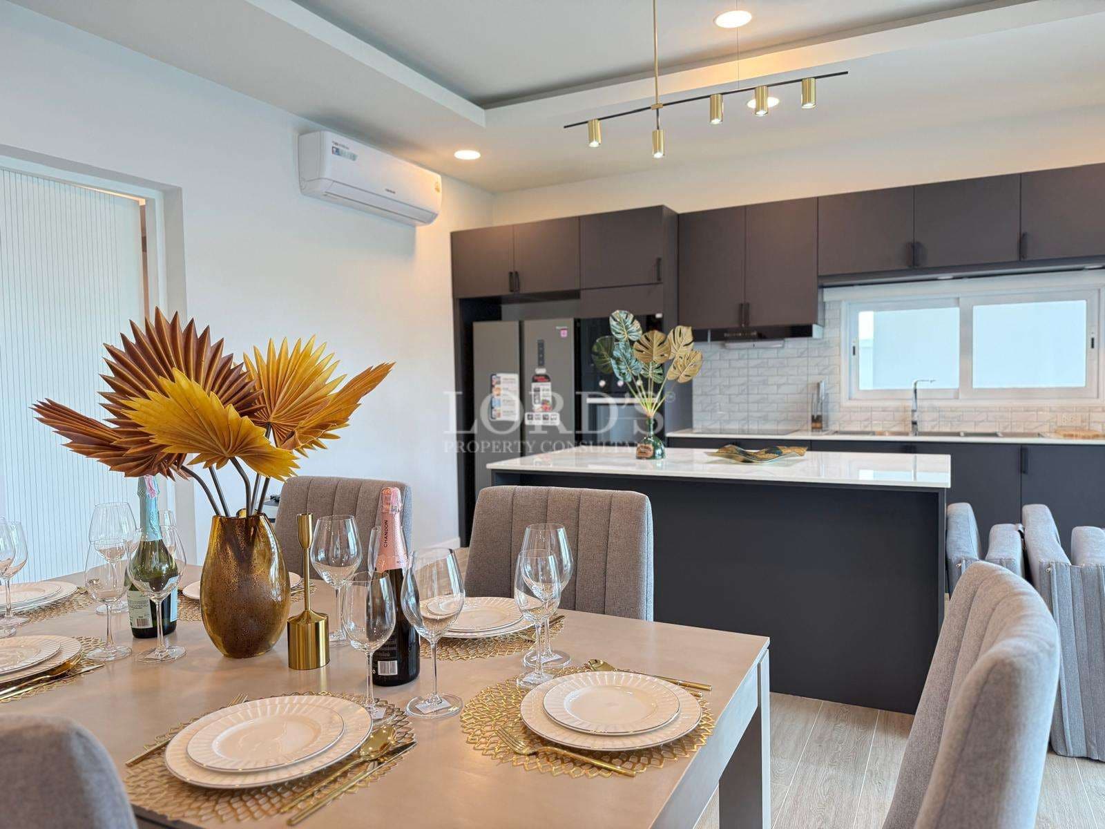 Modern open-plan kitchen and dining area with island counter, contemporary cabinets, and stylish table setting.