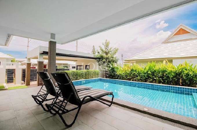 Private poolside area with sun loungers, covered terrace, and landscaped greenery.