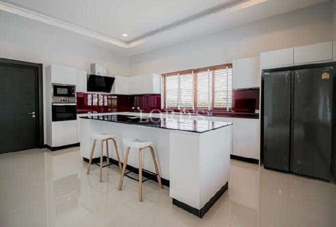 Modern kitchen with white cabinetry, central island, built-in appliances, and bar seating.