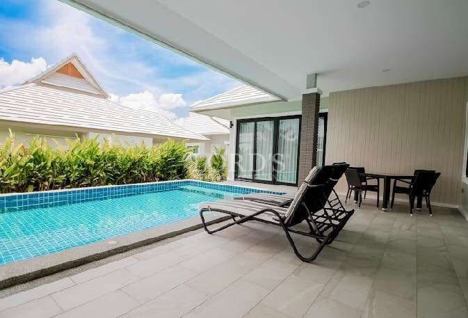 Private poolside terrace with sun loungers, outdoor dining area, and modern villa setting.