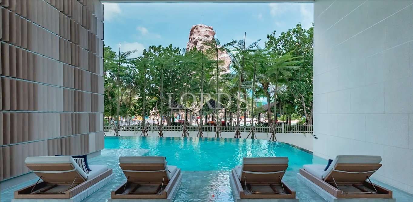 Resort-style swimming pool with sun loungers surrounded by lush tropical greenery.