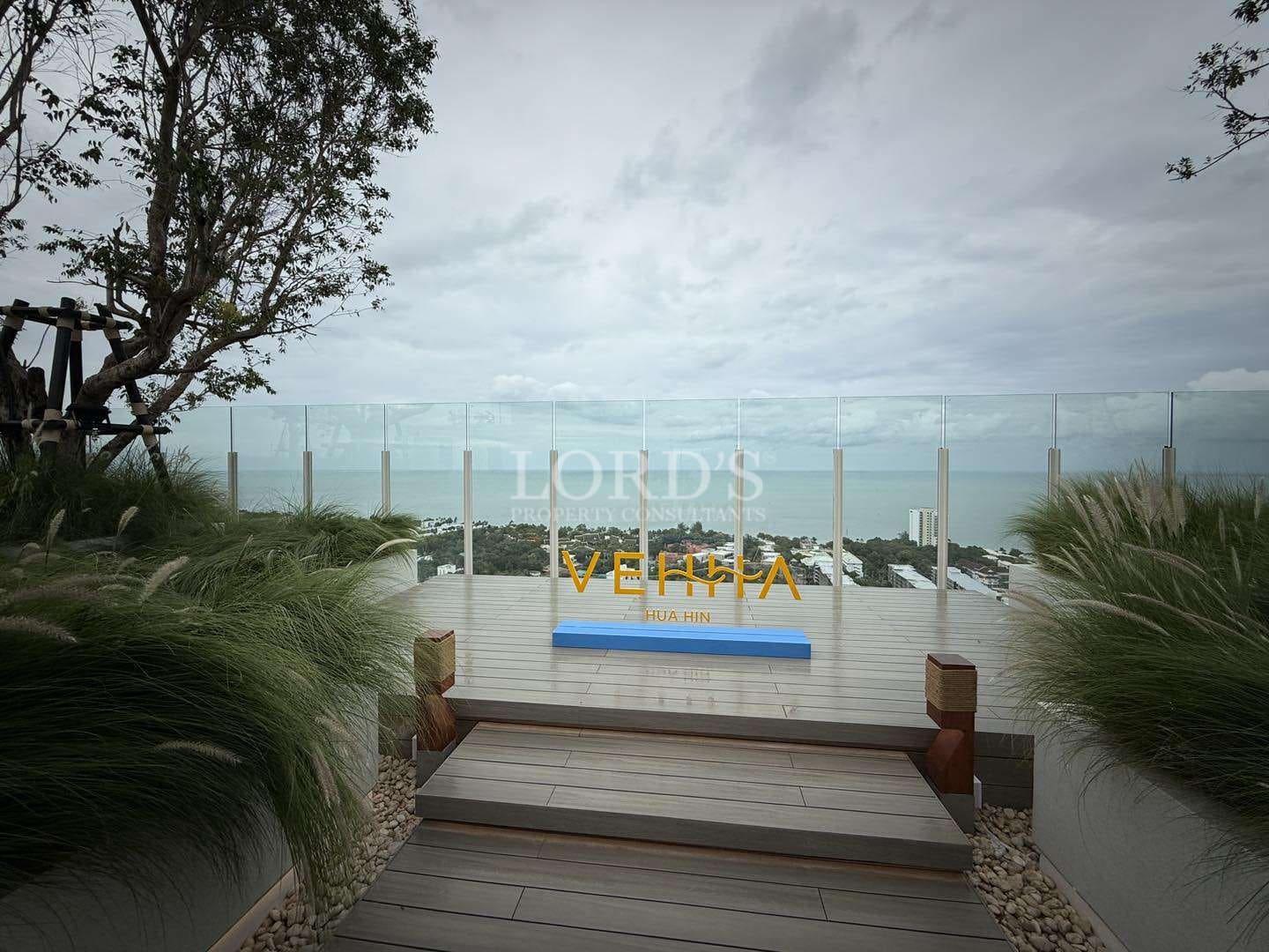 Scenic rooftop viewpoint with glass railing overlooking the sea and city below.