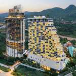 Aerial view of a modern luxury condominium complex with high-rise towers and mountain surroundings at sunset.