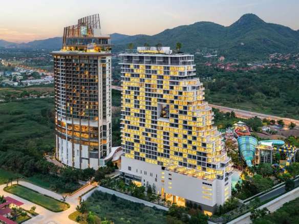 Aerial view of a modern luxury condominium complex with high-rise towers and mountain surroundings at sunset.