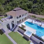 Aerial view of a luxury hillside villa with private swimming pool, terrace lounge area, and landscaped garden.